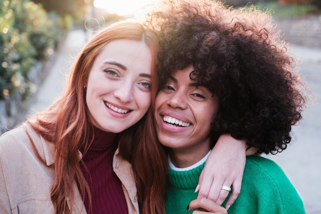 Close-up of two young women hugging at sunset outdoors. Concept lifestyle, friendship, smiles