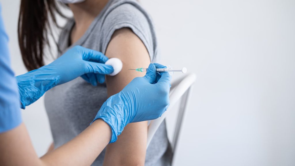 Hand of young woman nurse, doctor giving syringe vaccine, inject shot to Asian arm's patient